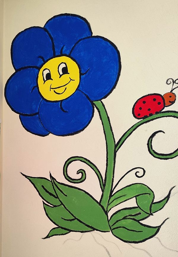 Gemalte blaue Blume mit lachendem Gesicht und einem Marienkäfer am Stiel