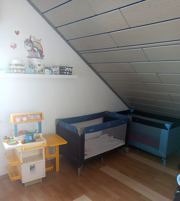 Kinder-Spielküche neben zwei Reisebettchen unter der Dachschräge