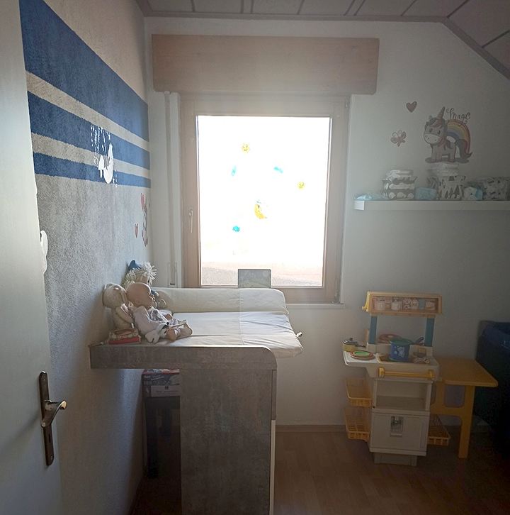 Wickelkommode vor dem Fenster, daneben eine Kinder-Spielküche